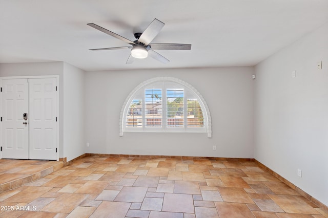 spare room featuring a ceiling fan and baseboards