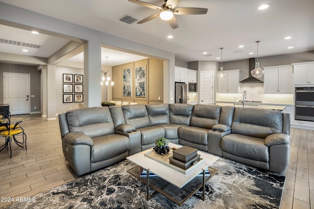 living room with light hardwood / wood-style flooring and ceiling fan with notable chandelier