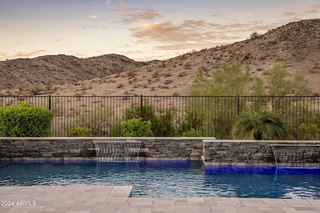 pool at dusk with a mountain view and pool water feature