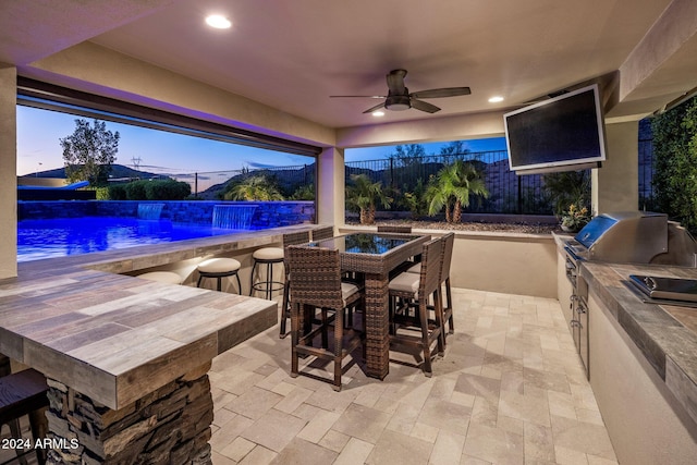 patio terrace at dusk with an outdoor kitchen and ceiling fan