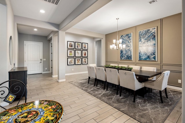 dining area with light hardwood / wood-style flooring and an inviting chandelier