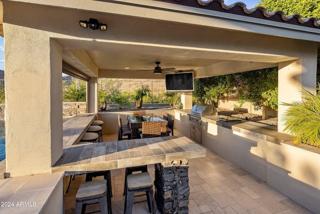 view of patio / terrace featuring exterior bar, exterior kitchen, grilling area, and ceiling fan