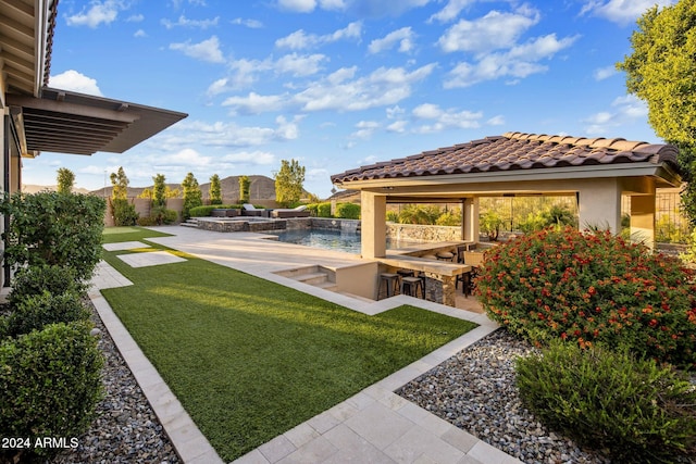 view of yard with exterior kitchen, pool water feature, and exterior bar