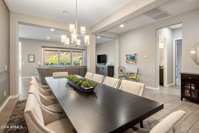 dining area featuring light hardwood / wood-style floors, an inviting chandelier, and beam ceiling