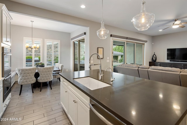 kitchen with light hardwood / wood-style flooring, white cabinetry, sink, and hanging light fixtures