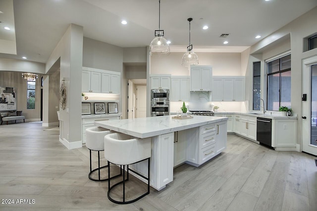 kitchen featuring a kitchen island, white cabinetry, stainless steel appliances, and light hardwood / wood-style flooring