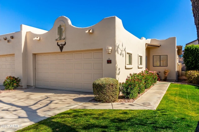 pueblo-style home with a garage and a front lawn