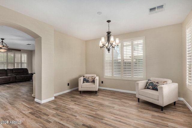 9566 N 83rd Dr, Peoria, AZ 85345 - living area featuring visible vents, baseboards, arched walkways, wood finished floors, and ceiling fan with notable chandelier
