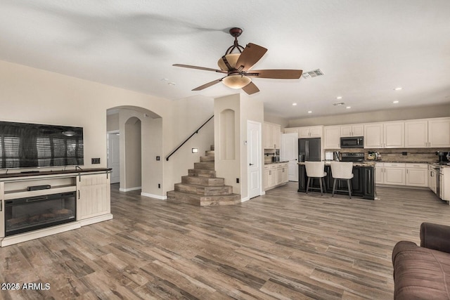 9566 N 83rd Dr, Peoria, AZ 85345 - living room featuring recessed lighting, arched walkways, visible vents, and wood finished floors