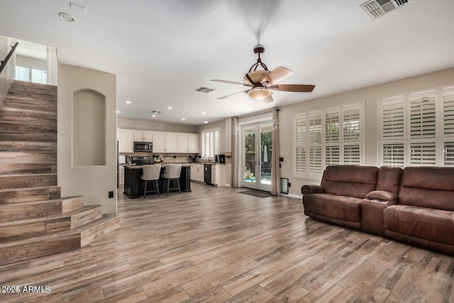 9566 N 83rd Dr, Peoria, AZ 85345 - living room featuring stairway, visible vents, ceiling fan, and light wood-style floors