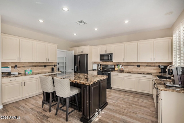 9566 N 83rd Dr, Peoria, AZ 85345 - kitchen with black appliances, white cabinets, a kitchen island, and tasteful backsplash