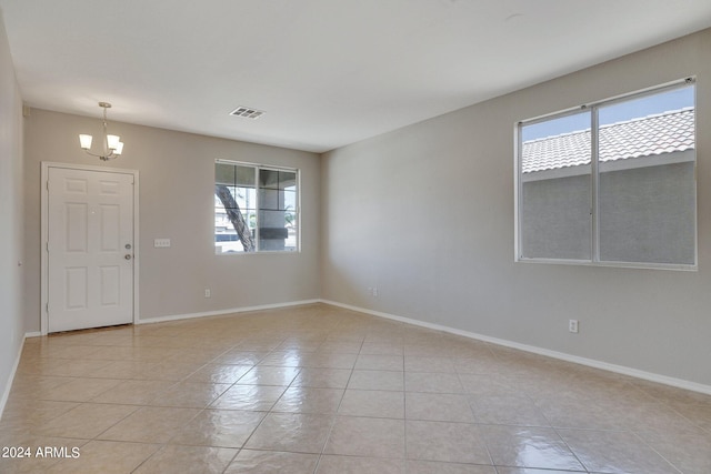 tiled empty room featuring a chandelier