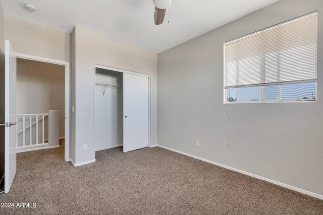 unfurnished bedroom featuring a closet, dark colored carpet, and ceiling fan