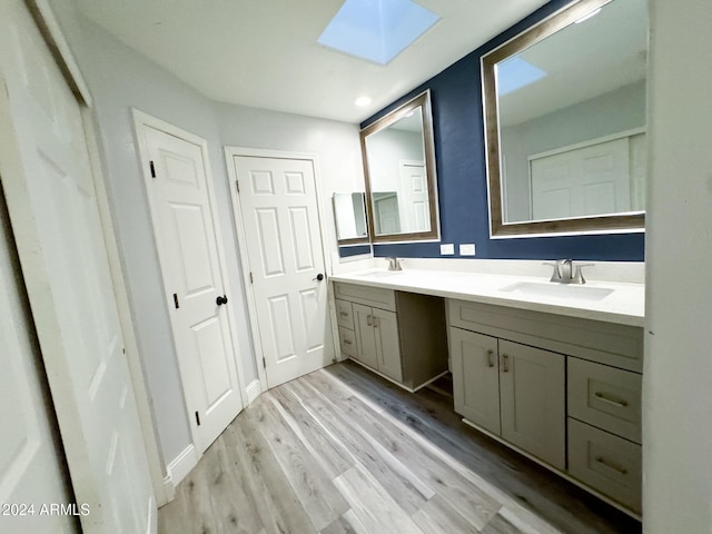 bathroom with vanity, a skylight, and hardwood / wood-style flooring