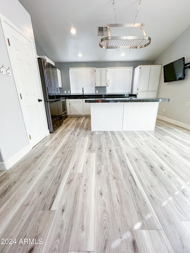 kitchen with stainless steel appliances, white cabinetry, sink, and light hardwood / wood-style flooring