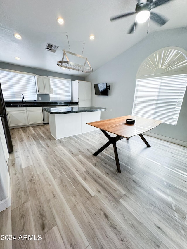 kitchen with white cabinetry, a center island, dishwasher, light hardwood / wood-style flooring, and vaulted ceiling