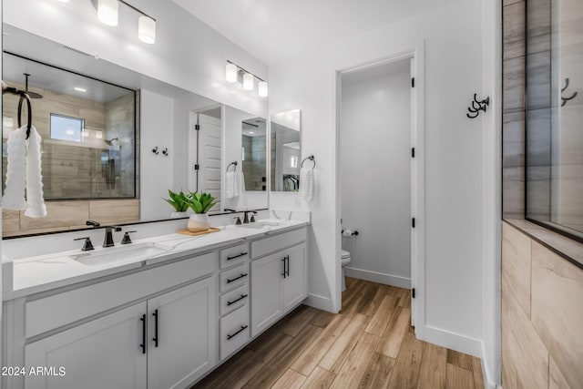 bathroom featuring vanity, hardwood / wood-style floors, tiled shower, and toilet