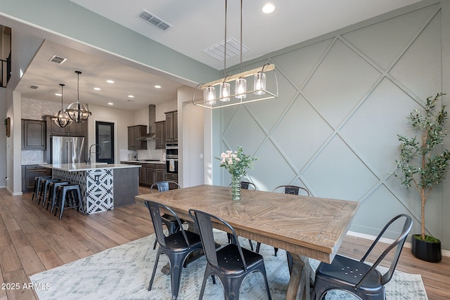 22771 N 98th Dr, Peoria, AZ 85383 - dining space with a chandelier, light wood-type flooring, baseboards, recessed lighting, and a decorative wall