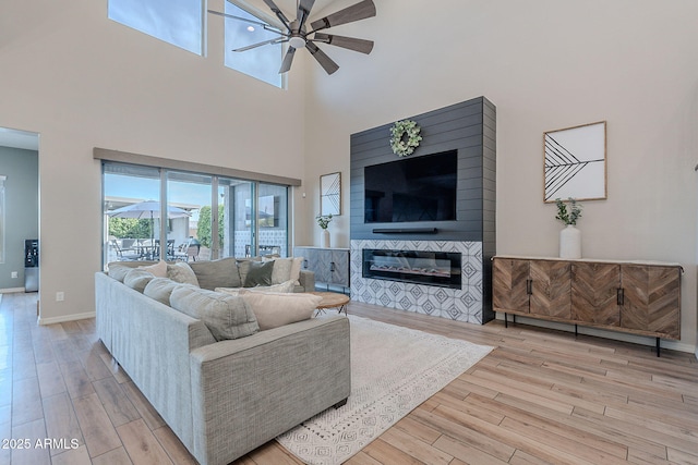 22771 N 98th Dr, Peoria, AZ 85383 - living room with wood finished floors, a ceiling fan, a glass covered fireplace, a towering ceiling, and baseboards