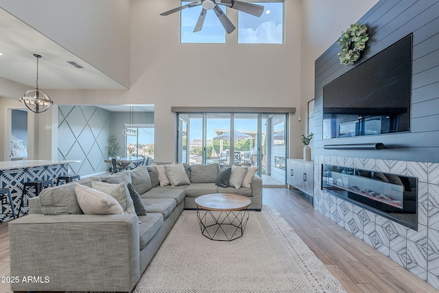 22771 N 98th Dr, Peoria, AZ 85383 - living area with wood finished floors, a chandelier, a ceiling fan, a tile fireplace, and a high ceiling