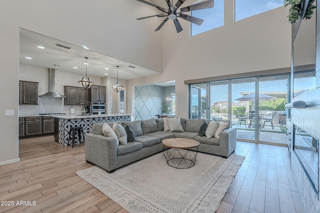 22771 N 98th Dr, Peoria, AZ 85383 - living area featuring a chandelier, light wood-style flooring, a ceiling fan, a towering ceiling, and recessed lighting