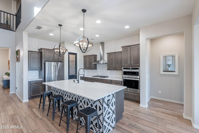 22771 N 98th Dr, Peoria, AZ 85383 - kitchen with wall chimney exhaust hood, stainless steel appliances, a chandelier, tasteful backsplash, and a breakfast bar