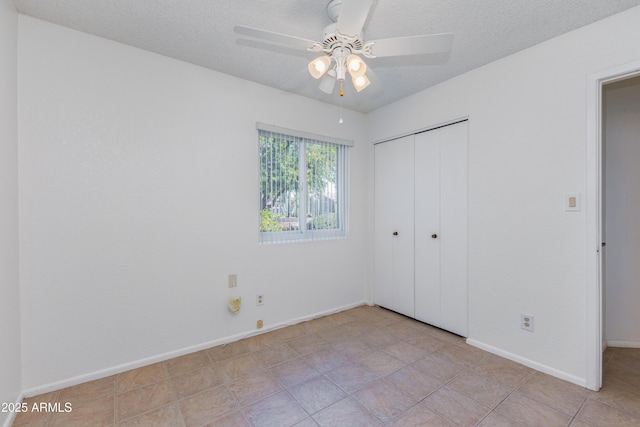 unfurnished bedroom with ceiling fan, light tile patterned flooring, a textured ceiling, and a closet