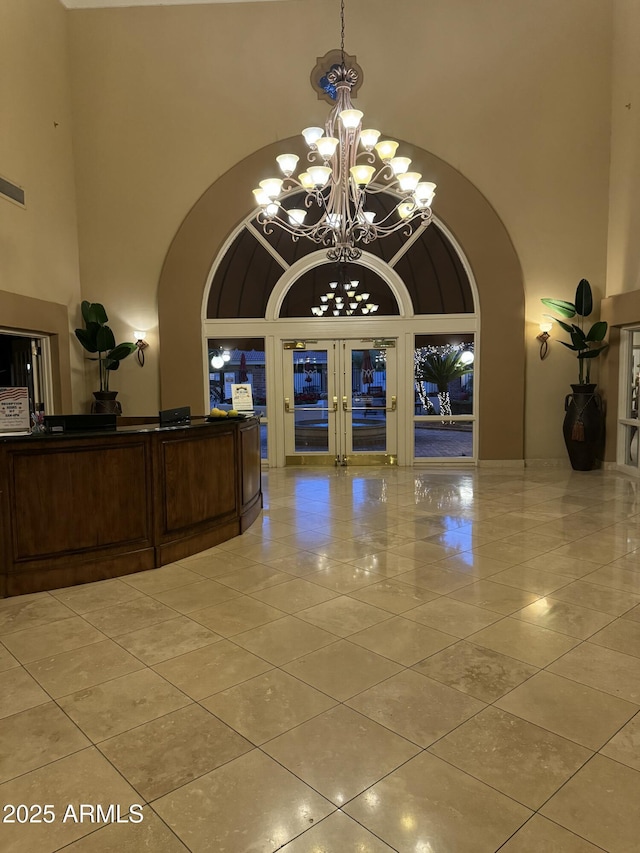 interior space featuring a towering ceiling, a chandelier, and french doors