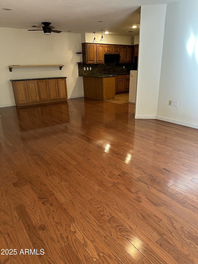 unfurnished living room with ceiling fan and dark hardwood / wood-style flooring