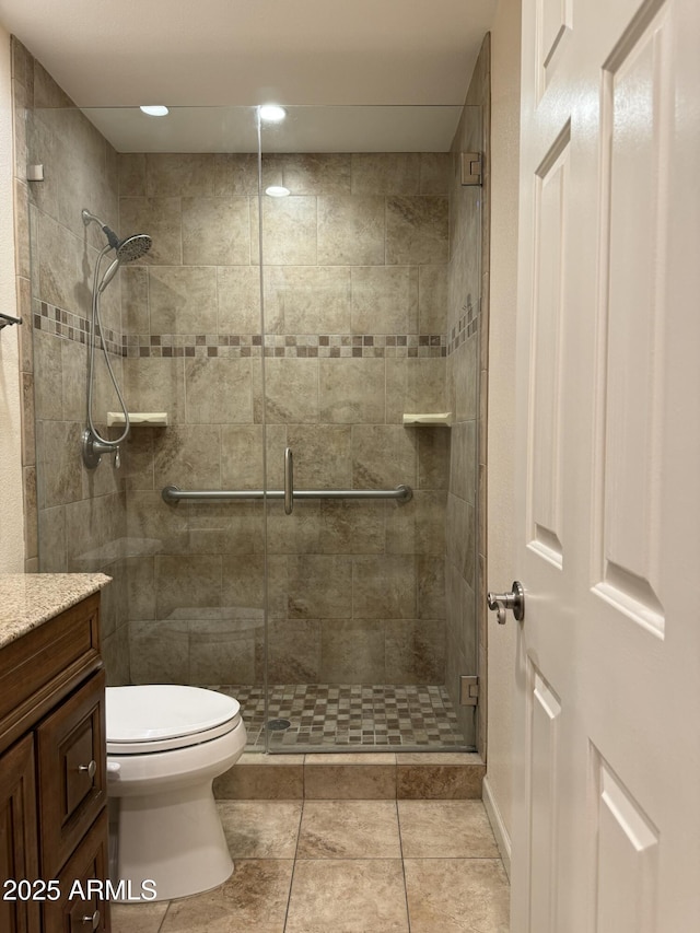 bathroom with vanity, a shower with shower door, tile patterned floors, and toilet