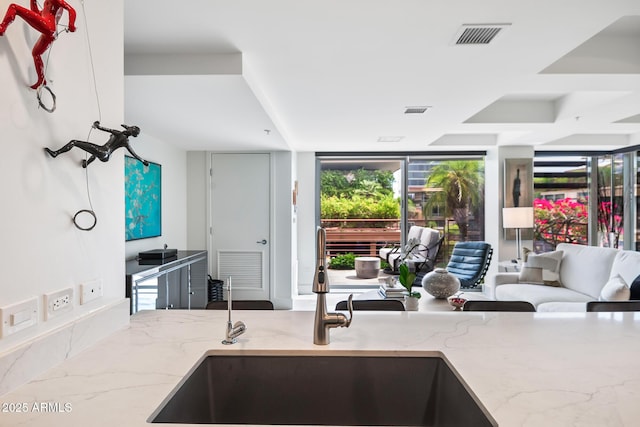 7141 E Rancho Vista Dr Unit 6007, Scottsdale, AZ 85251 - kitchen with a sink, light stone counters, open floor plan, and expansive windows