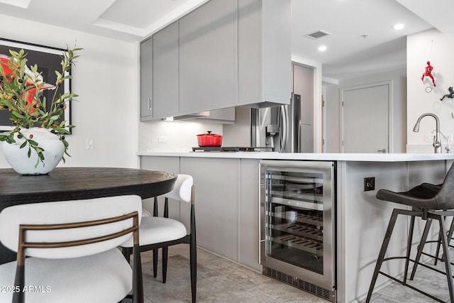7141 E Rancho Vista Dr Unit 6007, Scottsdale, AZ 85251 - kitchen featuring beverage cooler, gray cabinetry, a peninsula, a breakfast bar area, and recessed lighting