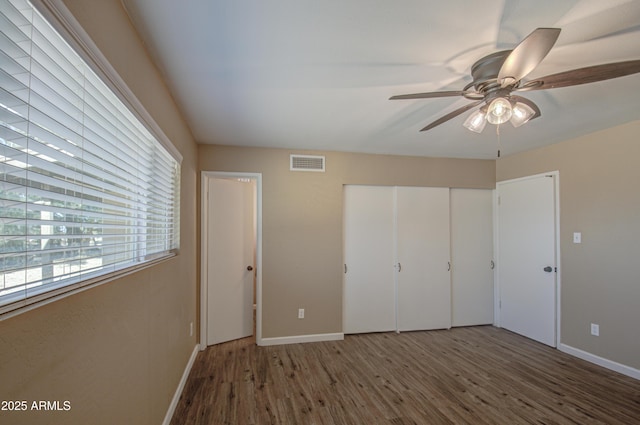 unfurnished bedroom featuring a closet, dark hardwood / wood-style floors, and ceiling fan