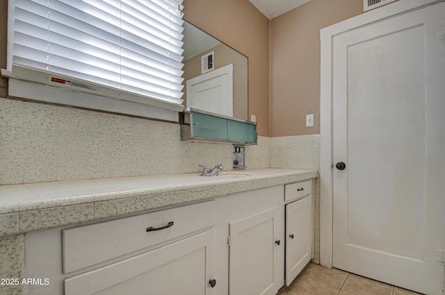 bathroom featuring tile patterned flooring, vanity, and tasteful backsplash