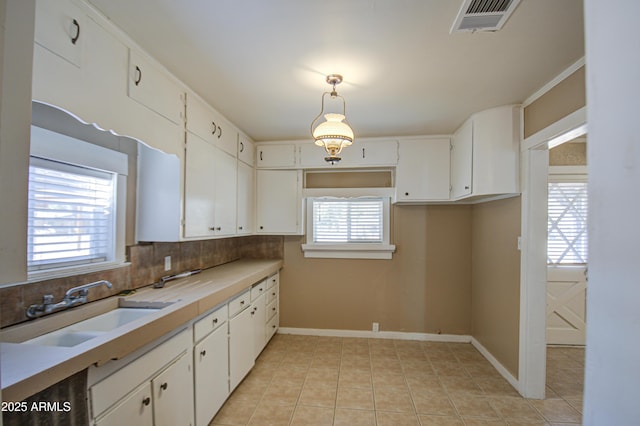 kitchen with a healthy amount of sunlight, decorative light fixtures, sink, and white cabinets