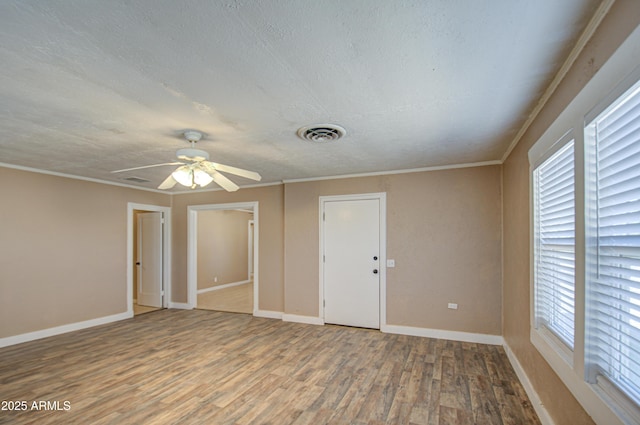 empty room featuring wood-type flooring, ornamental molding, a textured ceiling, and ceiling fan