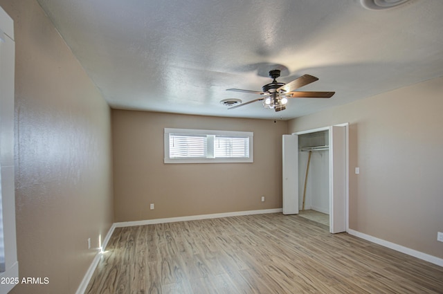 unfurnished bedroom with ceiling fan, a closet, light hardwood / wood-style flooring, and a textured ceiling