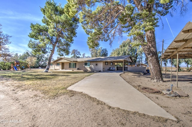 view of front facade with a carport, a playground, and a front yard