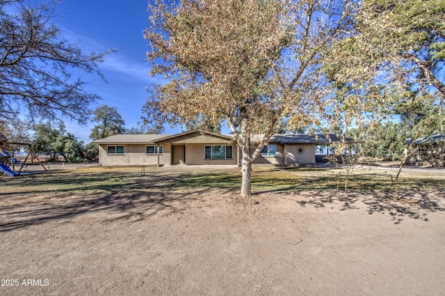 ranch-style home with a playground and a front lawn