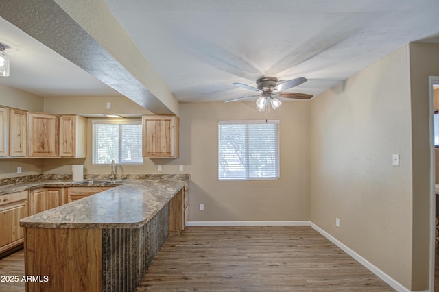 kitchen featuring sink, ceiling fan, kitchen peninsula, light brown cabinets, and light hardwood / wood-style flooring