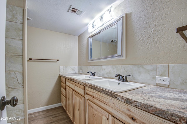 bathroom with decorative backsplash, vanity, wood-type flooring, and a textured ceiling