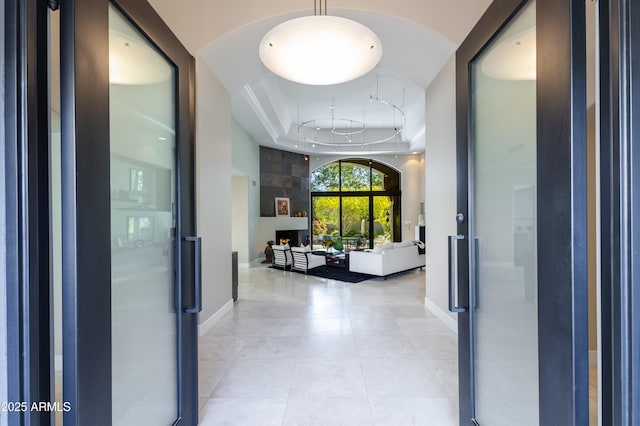 hall with light tile patterned floors and a tray ceiling