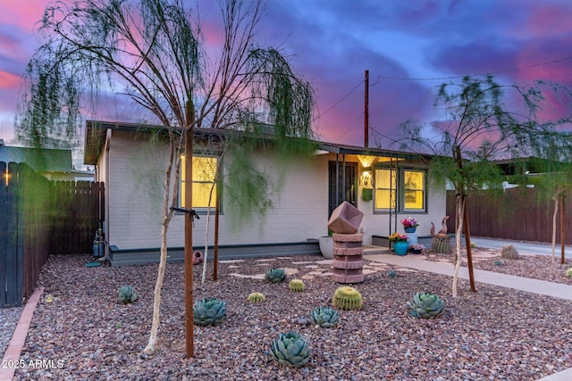 view of front of property featuring fence and brick siding
