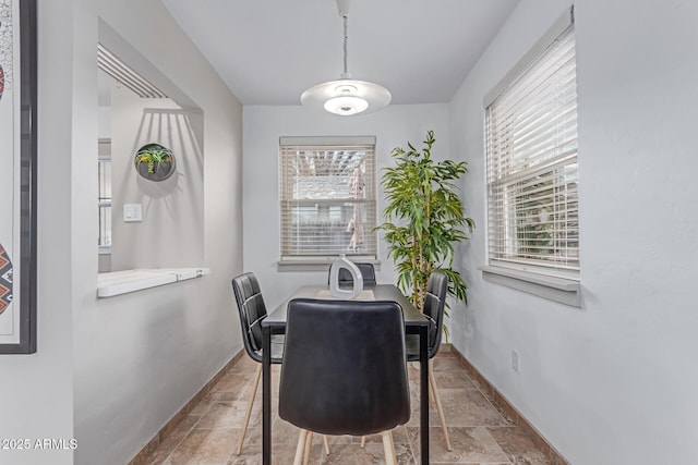 dining space featuring stone tile floors, baseboards, and a wealth of natural light