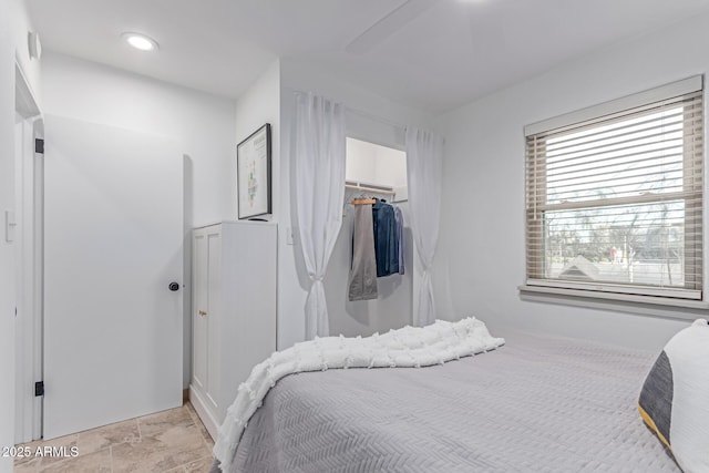 bedroom featuring a walk in closet, a ceiling fan, a closet, and stone finish flooring