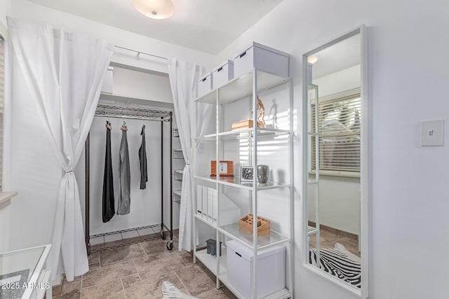 walk in closet featuring stone finish floor