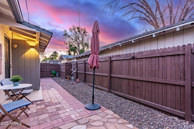 patio terrace at dusk featuring a fenced backyard