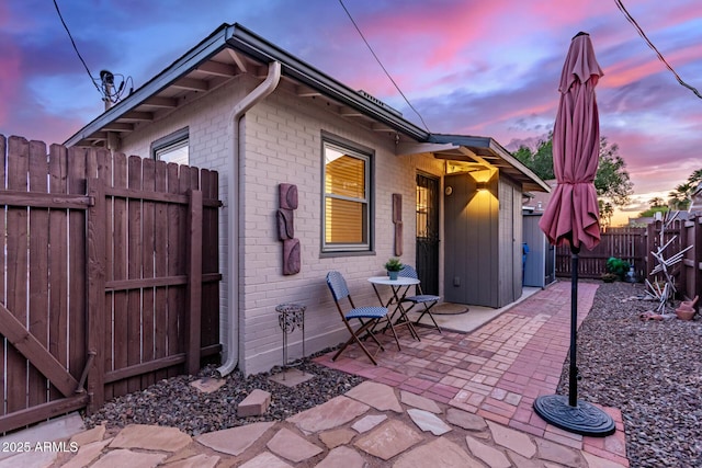 exterior space with brick siding, a fenced backyard, and a patio area