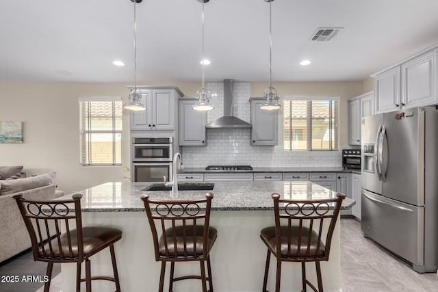 kitchen featuring appliances with stainless steel finishes, sink, pendant lighting, and wall chimney exhaust hood