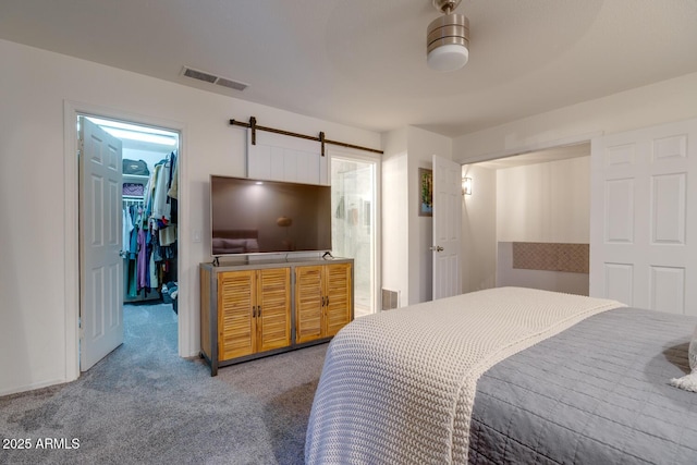 bedroom featuring a closet, a spacious closet, a barn door, and carpet flooring